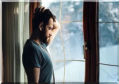 Sad man near the window thinking about the wounds that infidelity leaves 